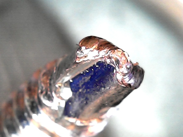Detail of damaged self-drilling screw tip showing metal deformation and melting due to high speed and high force driving into 2mm steel.